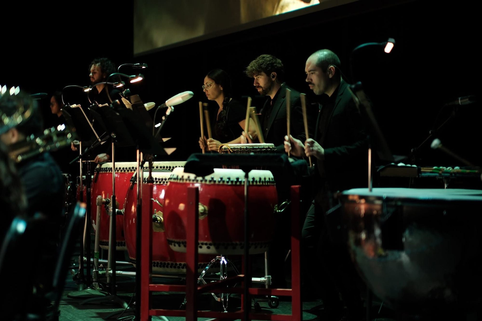 Percussionists performing on Chinese tanggu drums with an orchestra.